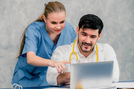 快乐的医生和护士在医院办公室用笔记本电脑工作图片