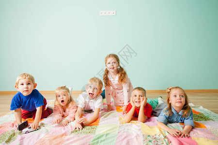六个可爱而兴奋的孩子躺在蓝色背景的地板上图片