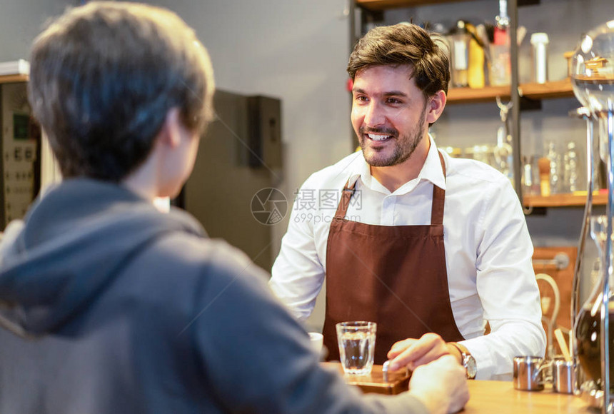 微笑迷人的留着胡子的咖啡师服务员站在柜台后面图片
