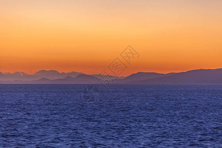 希腊海平地线上橙色天空和爱琴海岛屿的明图片