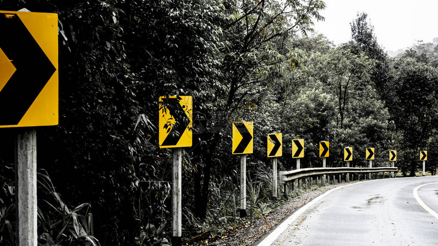 在森林和山丘的乡村公路上右转信号道路图片