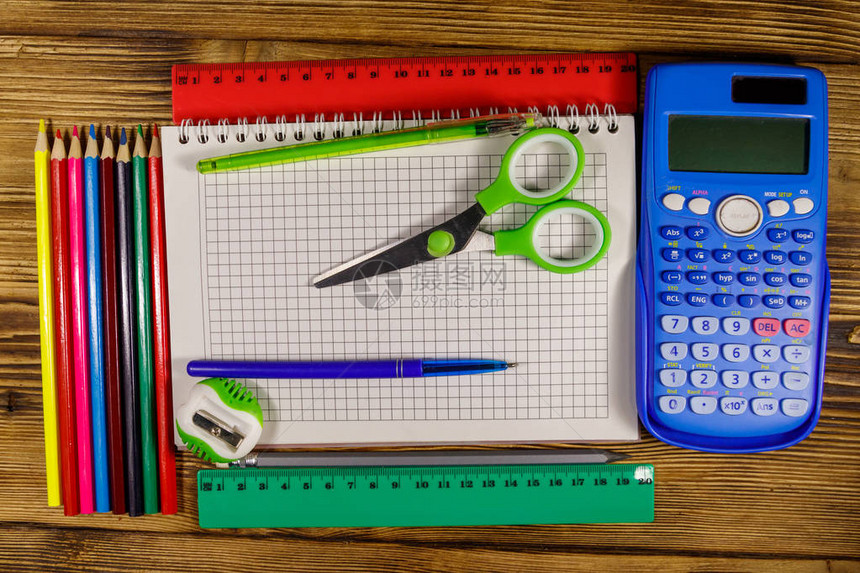 一套学校文具用品木桌上的空白记事本计算器尺子铅笔钢笔剪刀和磨图片