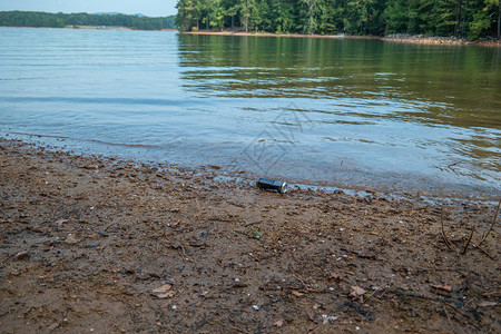 一个废弃的用过的饮料罐在夏天被倾倒在靠近湖水的海滩上图片