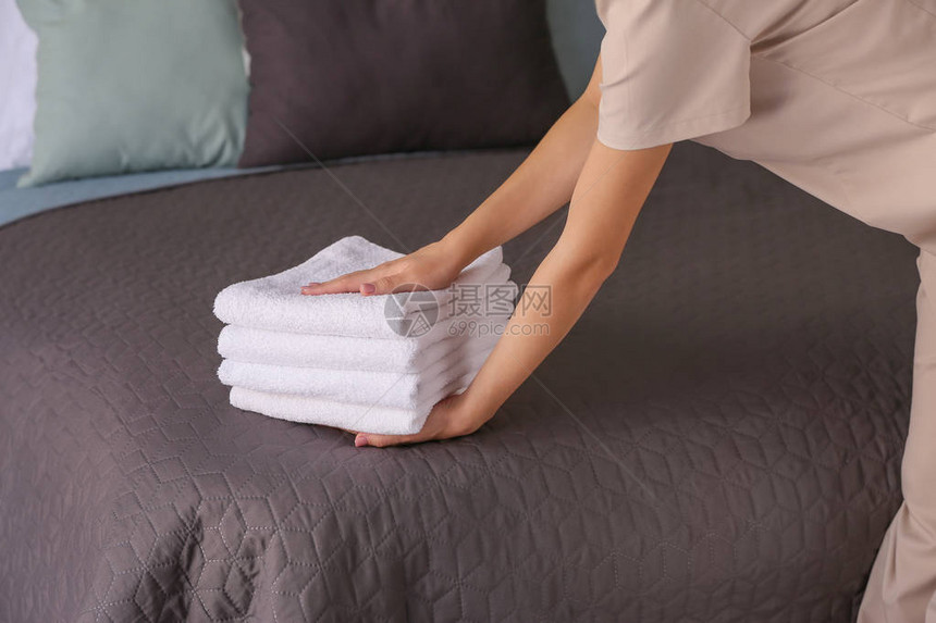 女管家把干净的毛巾放在床上图片