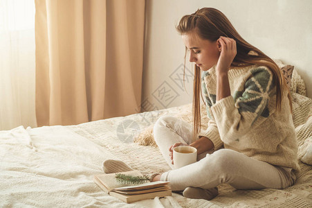 美丽的女孩正在读一本书里面有一杯热茶秋冬图片