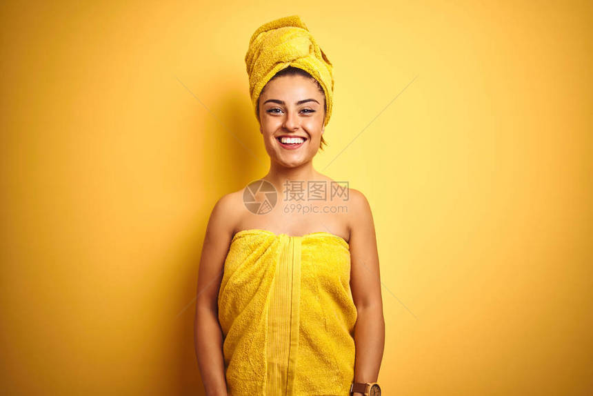 年轻美女洗完澡后在孤立的黄色背景上穿着毛巾图片