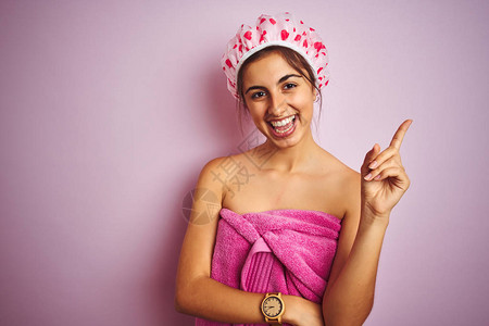 年轻漂亮的女人在粉红色的孤立背景下洗完澡后穿着浴巾图片
