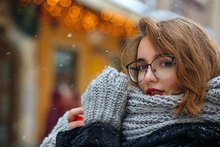 红嘴唇的光荣黑发女人在下雪时在街上图片
