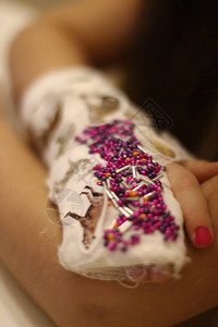 在一个小女孩的手上涂粉刷用珠子和贴图片