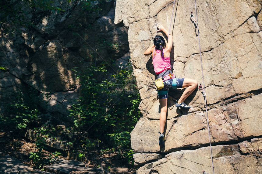 女孩攀登了花岗岩攀岩者在自然地形上列图片