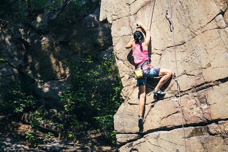 女孩攀登了花岗岩攀岩者在自然地形上列背景图片