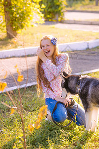 有红长头发的少女可爱女孩在秋天公园和她的哈斯基育种狗一起散图片