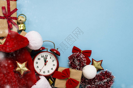 红色闹钟圣诞老人帽子圣诞树装饰品蓝色背景上的礼物图片