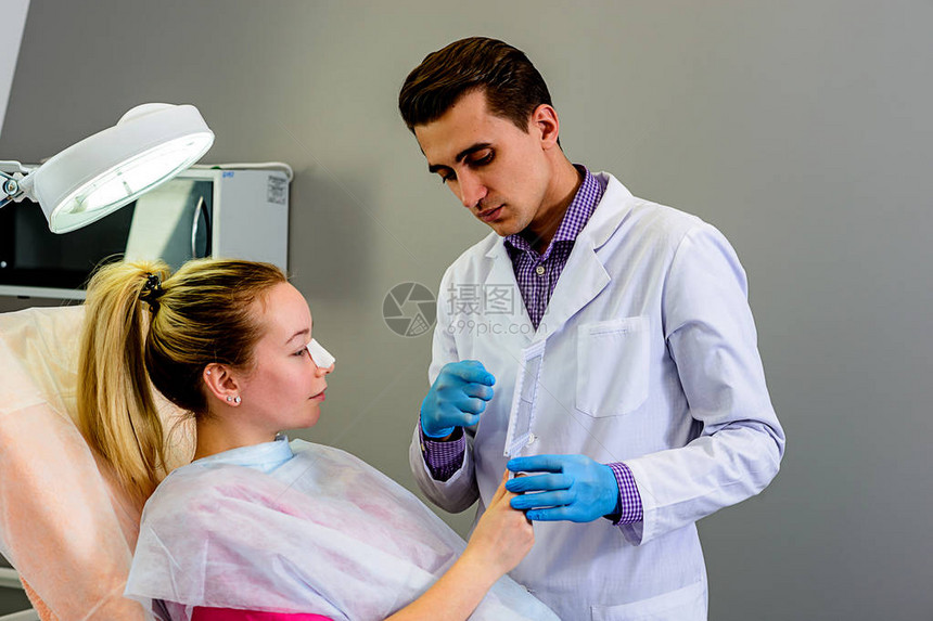 医生准备为患者进行鼻子整形手术患者与整形外科专家交谈病人照着图片