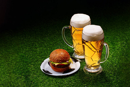 两杯啤酒和两杯汉堡放在绿色图片