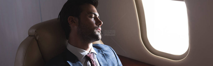 英俊的商人在出差期间睡在飞机上图片