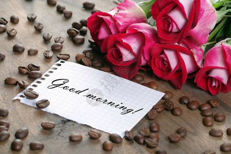 咖啡概念玫瑰和咖啡杯咖啡和一束玫瑰木制的桌子上早上的咖啡和注图片
