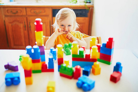 可爱的小女孩在家中幼儿园或学前班玩多彩塑料建筑块图片