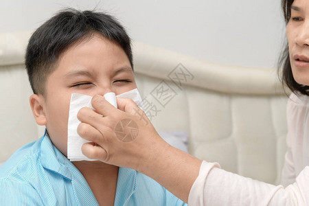 生病的亚洲儿童在母亲帮助他时用组织擦鼻涕或打扫鼻子保健发图片