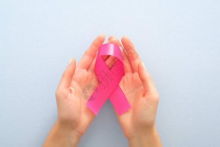 女手中的粉色乳腺癌认识丝带覆盖蓝背景图片