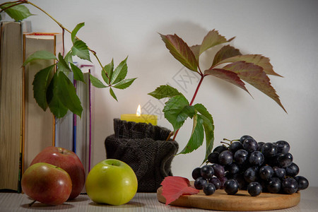 秋天的生活还有书本烧蜡烛成熟的葡萄苹果和白种树叶的野葡萄枝图片
