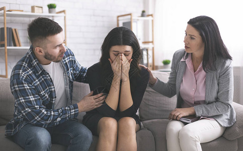 神经症丈夫和心理学家在婚姻咨询时安慰心烦意乱的哭泣妇女背景