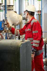 能源行业一名身着红色工作服和白色头盔的技术人员正在检查加热参数采暖配水技术电力行背景图片