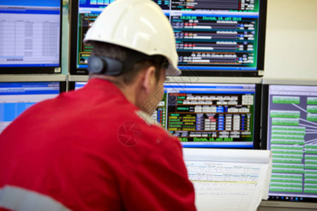 能源行业供暖系统的数字控制一名身着红色工作服和白色头盔的技术人员检查显示器上的加热参数监督控背景图片