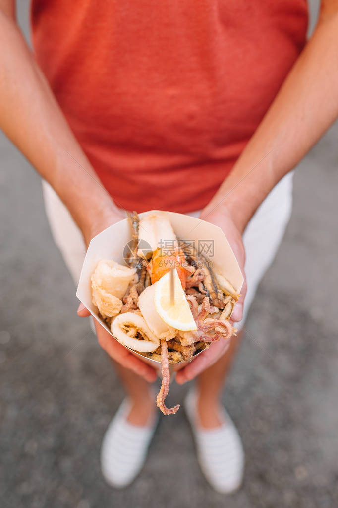 意大利街头食品在男手中烤海鲜鱼虾图片