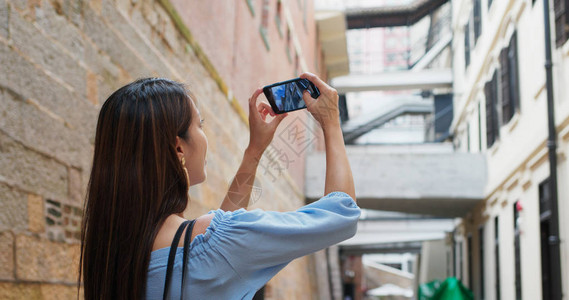 女游客访问香港城市并用手机拍照图片