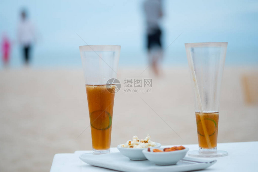 在海景背的海滩上放着一杯高冷冰茶和柠檬片豪华假期的概念图片