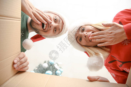 圣诞快乐的一对情侣在圣塔帽上开着圣诞礼物图片