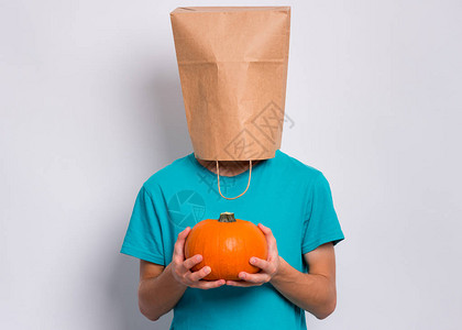 头戴纸袋的小男孩拿着橙色的新鲜小南瓜图片