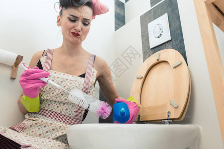 恶心的女士试图洗厕所用刷子抹去工作图片