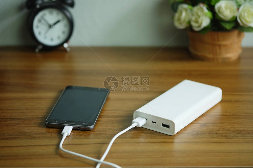 智能手机充电时用备电池或桌子木桌上的图片
