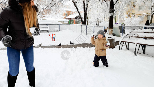 年轻快乐的金发女人在公园的操场上玩雪球图片