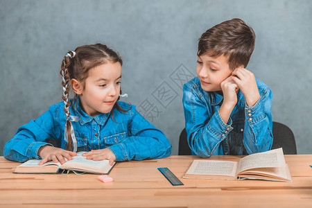 教育与学校概念阅读过程儿童坐在灰色背景的书桌旁a学生图片