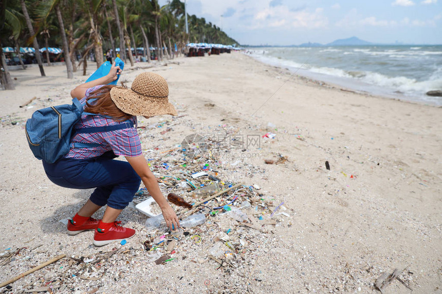 一名戴帽子的志愿旅游志愿者正在清理肮脏海滩上的垃圾和塑料垃圾图片