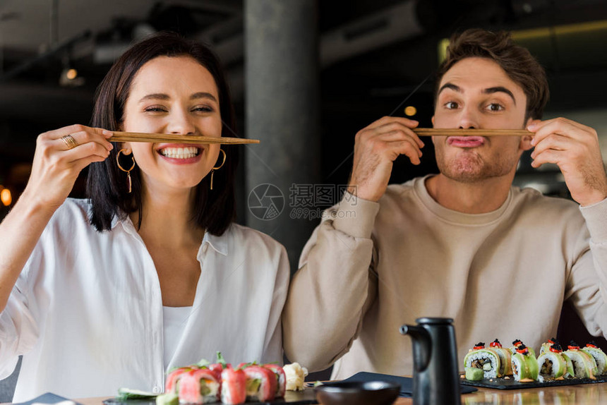 帅的男汉在寿司酒吧和快乐的女孩坐在一起时图片