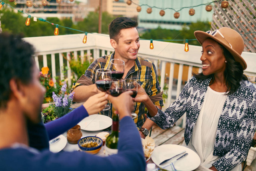 千万朋友们享受着一杯红酒在外面吃晚饭在屋顶的院子上为了感图片