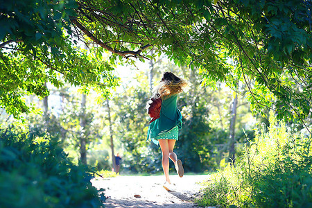夏天嬉戏的成年少女在公园里旋转跳跃欢快的美女模特图片