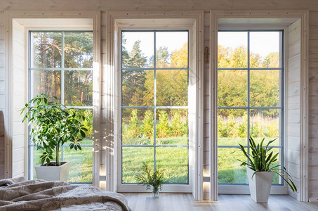 木屋内明亮的房间内部设有俯瞰秋季庭院的大窗户白色窗口中的秋景和花园图片