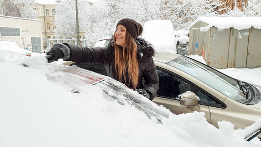 穿着夹克的微笑女孩清理了雪盖车图片