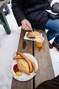 女人在参观雪山度假村时吃传统德国香肠和传统图片