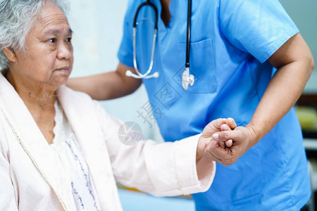 亚洲护士理疗师医生护理帮助和支持老年或老年妇人患者躺在医院病房的床上图片