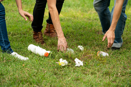 年轻人捡垃圾清理公共园草坪志愿者和环境保护单背景图片