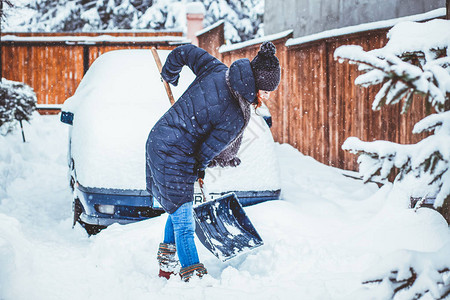 院子里拿着铲子扫雪的女人图片