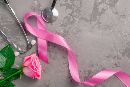 粉色丝带听诊器和粉红色玫瑰以具体背景为背景图片