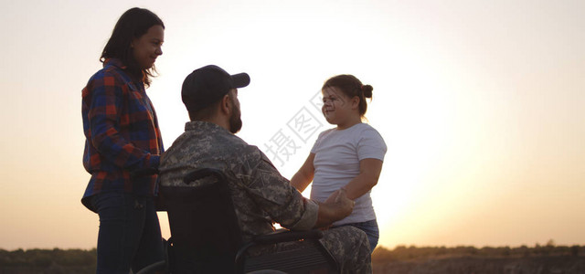 一名轮椅士兵在草地上亲吻妻子并拥抱图片