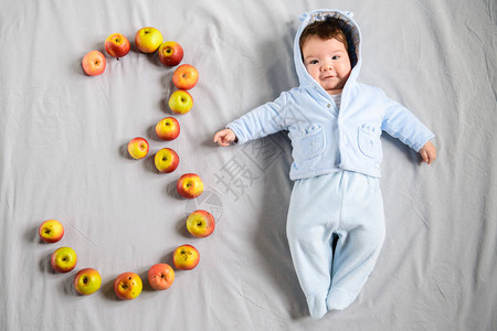 一个可爱的3个月大婴儿的肖像穿着白衣服躺在床上的图片